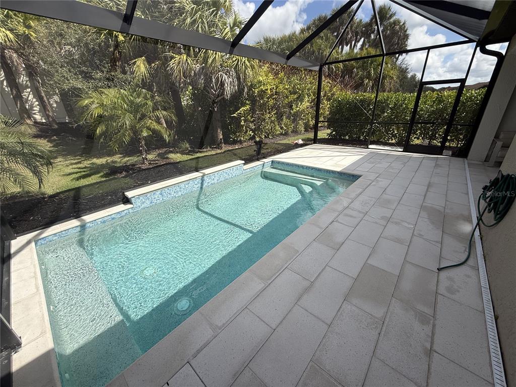 A rectangular swimming pool with blue tile accents sits on a paved patio inside a screen — 192 SOLIERA STREET, NOKOMIS, FL