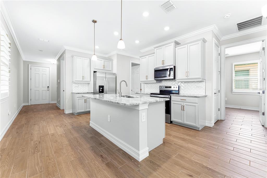 A modern kitchen features white cabinetry, a marble-topped island, and light wood-look tile flooring — 192 SOLIERA STREET, NOKOMIS, FL