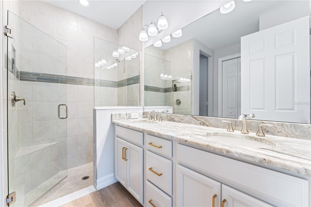 A bathroom features a glass-enclosed walk-in shower, a double vanity with stone countertops, and cabinetry — 192 SOLIERA STREET, NOKOMIS, FL