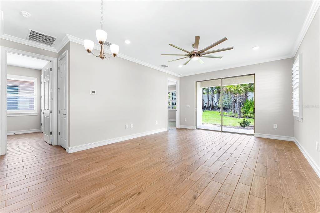 A bright room with wood-look tile flooring, a ceiling fan, and sliding glass doors to a yard — 192 SOLIERA STREET, NOKOMIS, FL