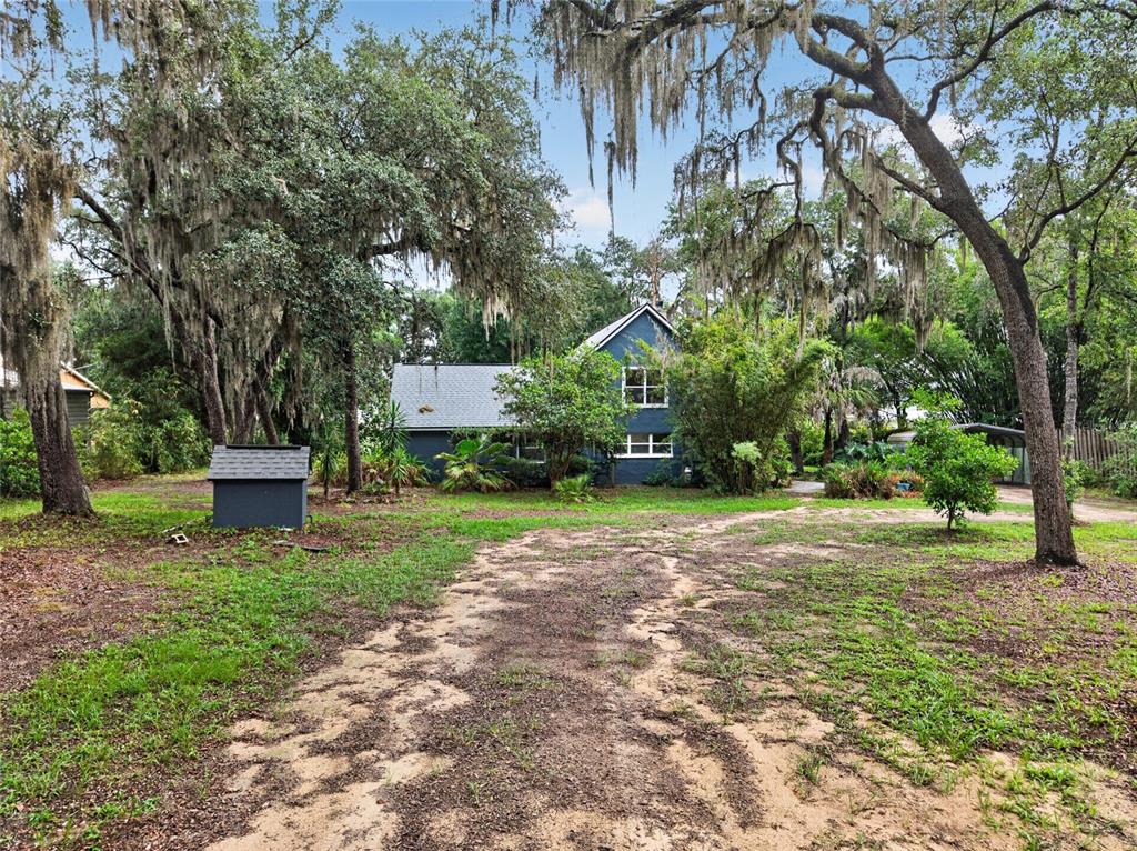 A blue two-story house sits on a large, wooded lot with a dirt driveway — 104 LONG POND WAY, HAWTHORNE, FL