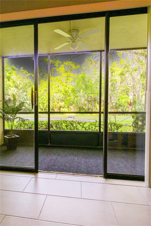 A view from a tiled room through sliding glass doors to a screened-in porch — 3232 LAKE PINE WAY E UNIT G1, TARPON SPRINGS, FL
