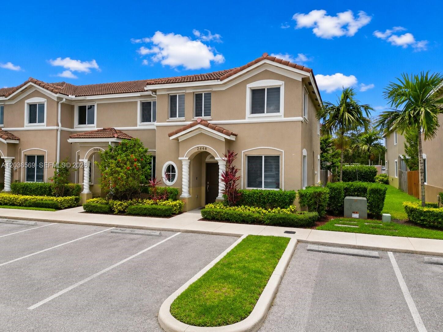 A two-story tan townhouse with a tiled roof and a small front garden — 2448 SE 10th Ct, Homestead FL 33035, HOMESTEAD, FL