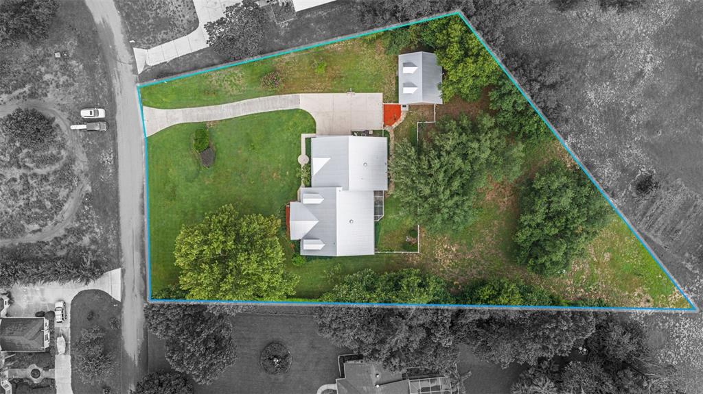This aerial view shows a residential property with a house, detached garage, and driveway — 12728 CYNTHIA LANE, CLERMONT, FL