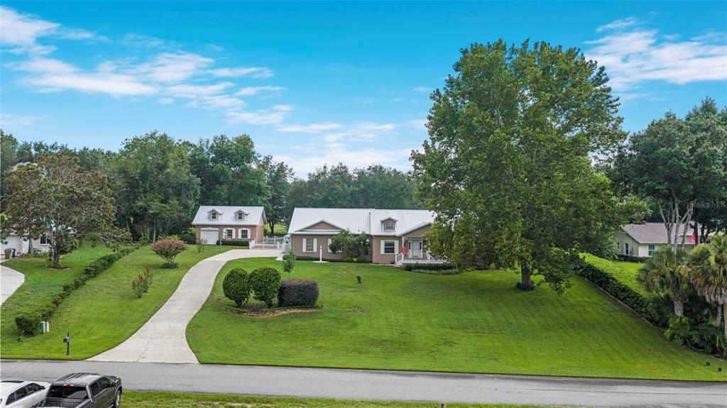 An aerial view shows a tan house with a metal roof and a detached garage — 12728 CYNTHIA LANE, CLERMONT, FL
