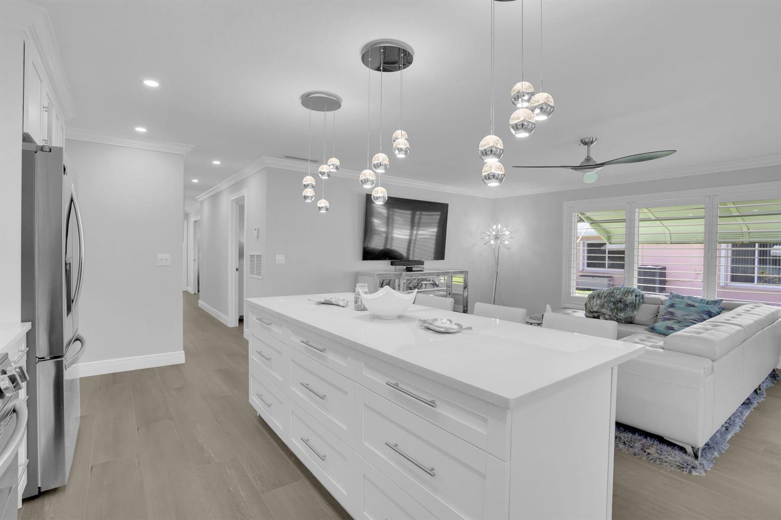 A modern white kitchen island sits in an open-concept living space with pendant lighting — 540 High Point Drive # A, Delray Beach FL 33445, DELRAY BEACH, FL
