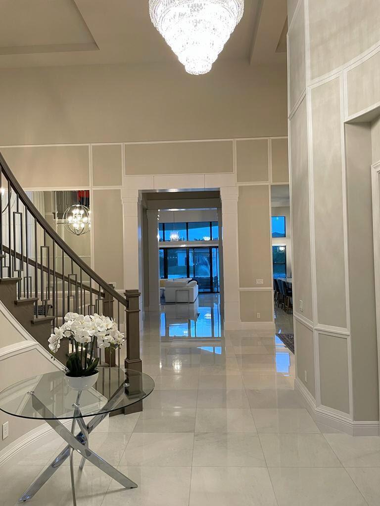 A bright foyer features a crystal chandelier, a glass table with orchids, and a staircase — 6930 NW 27th Avenue, Boca Raton FL 33496, BOCA RATON, FL