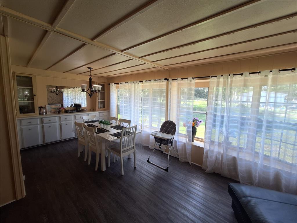 A dining room features a white table, chairs, a high chair, and large windows — 3911 LOURY DRIVE, WESLEY CHAPEL, FL