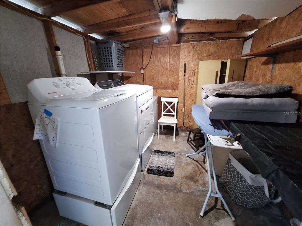 A laundry room features white appliances, plywood walls, and an exposed wood ceiling — 3911 LOURY DRIVE, WESLEY CHAPEL, FL