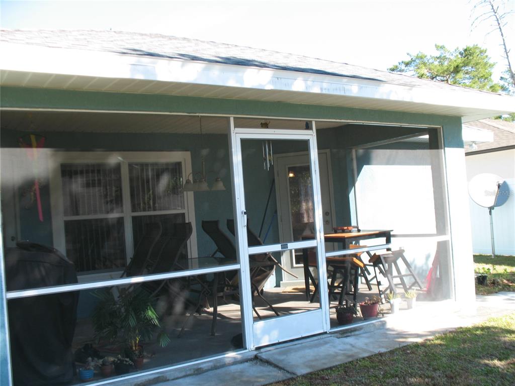 A screened-in patio features a white door, outdoor furniture, and a concrete floor — 3658 SW 127TH LANE ROAD, OCALA, FL