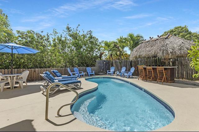 A kidney-shaped swimming pool sits on a patio with lounge chairs and a tiki bar — 309 E Calzada De Bougainville, Marathon FL 33050, MARATHON, FL