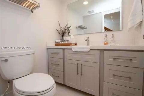 A bathroom features a white toilet, a light gray vanity with drawers, and a wall mirror — 933 NW 106th Ave Cir, Miami FL 33172, MIAMI, FL
