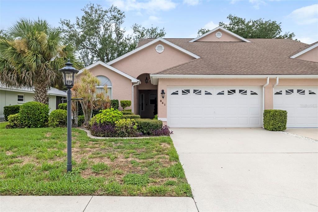 A single-story house with a peach-colored exterior, a two-car garage, and a landscaped front yard — 841 BAYPORT CIRCLE, VENICE, FL