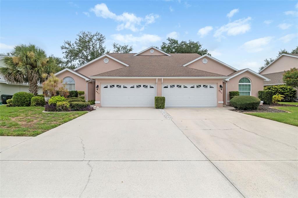A duplex house with two garage doors and a shared concrete driveway under a blue sky — 841 BAYPORT CIRCLE, VENICE, FL