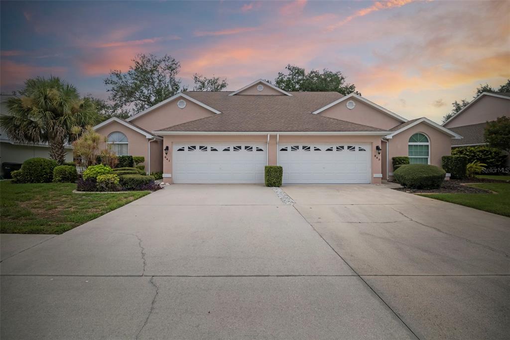 A duplex home with two white garage doors, a concrete driveway, and a sunset sky — 841 BAYPORT CIRCLE, VENICE, FL