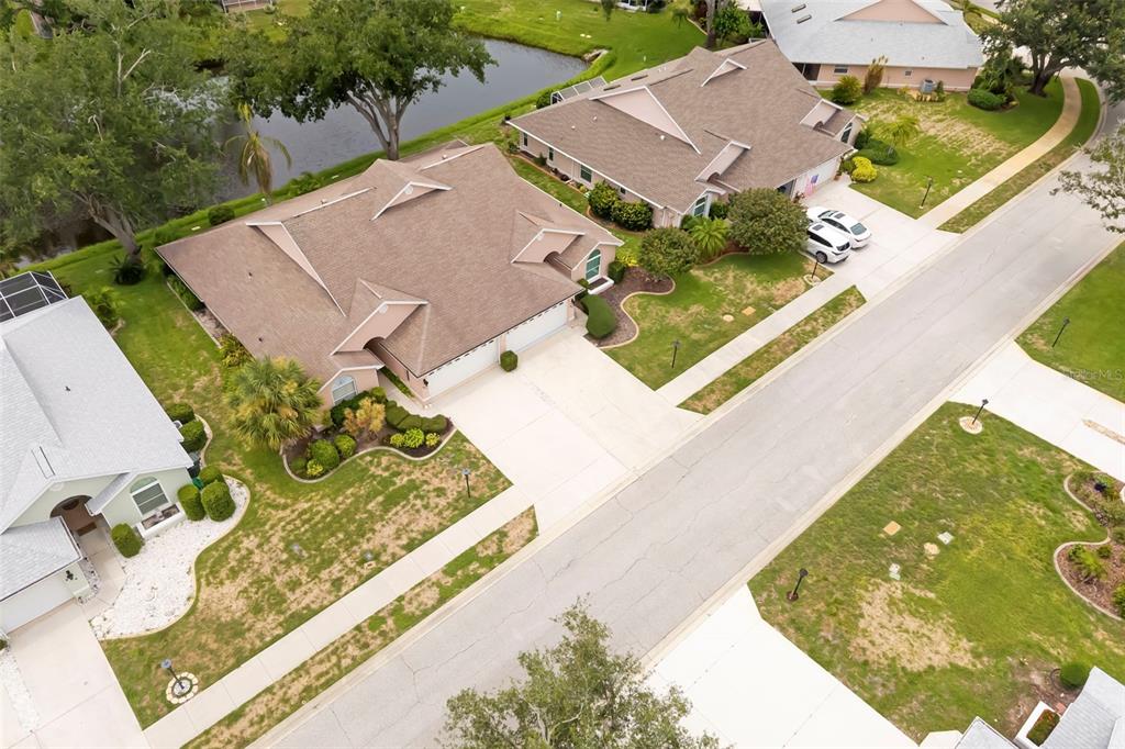 An aerial view shows several suburban houses with brown roofs and driveways near a pond — 841 BAYPORT CIRCLE, VENICE, FL