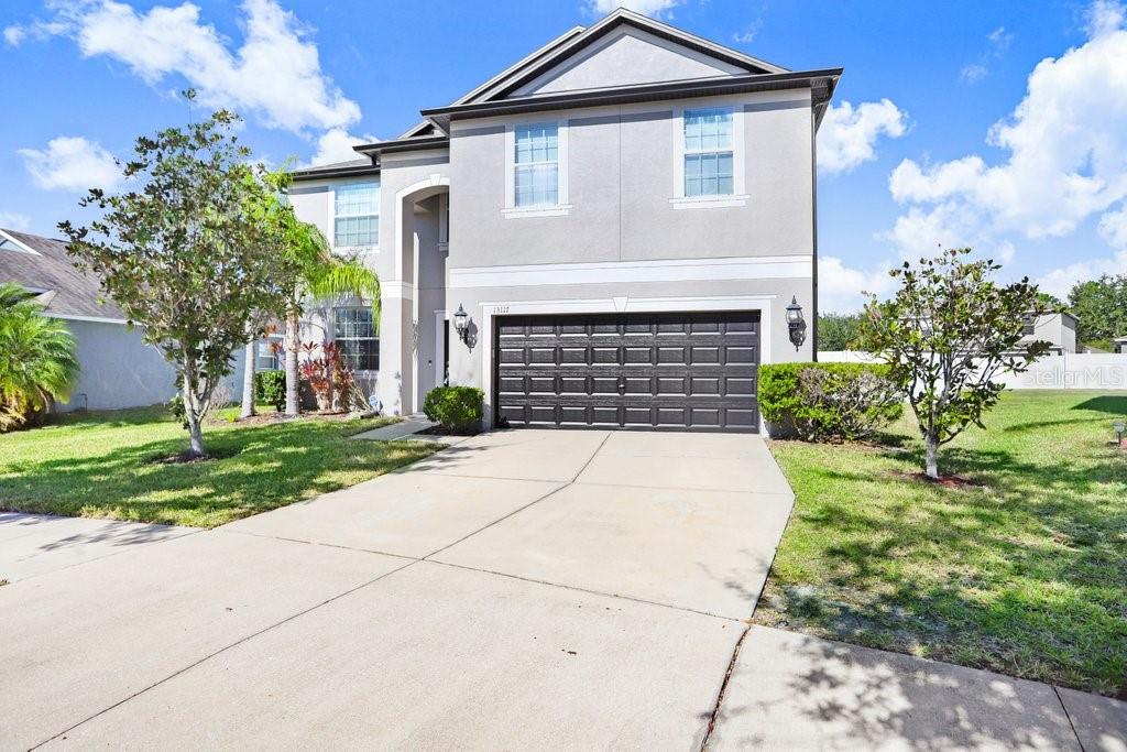A two-story house with a gray stucco exterior, a black garage door, and a concrete driveway — 13117 ROYAL PINES AVENUE, RIVERVIEW, FL