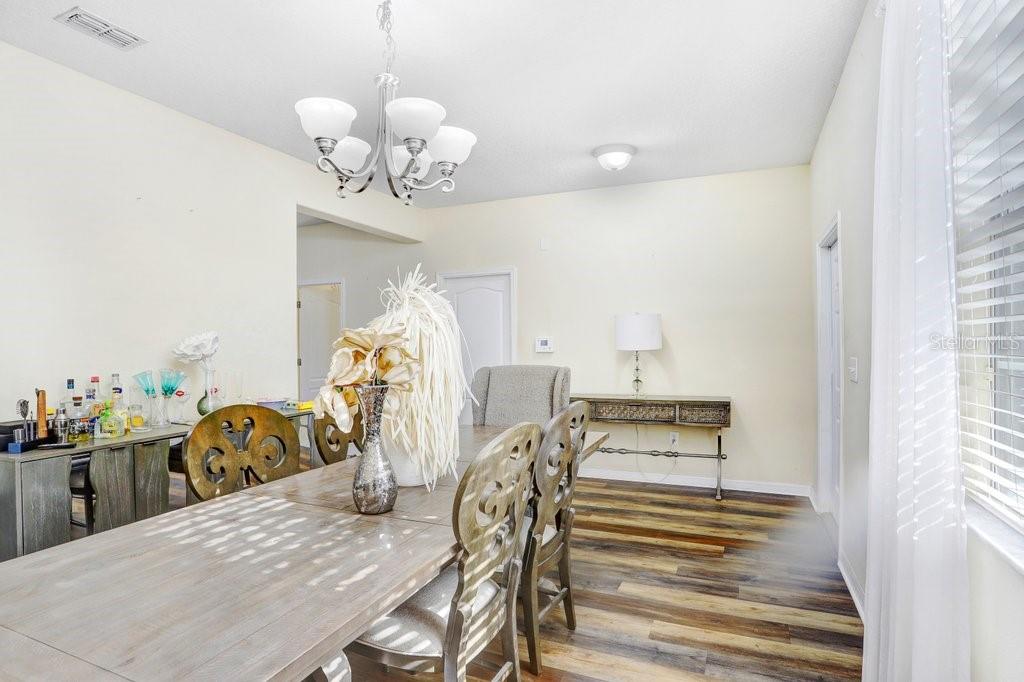 A dining room features a wooden table, decorative chairs, a chandelier, and wood-look flooring — 13117 ROYAL PINES AVENUE, RIVERVIEW, FL