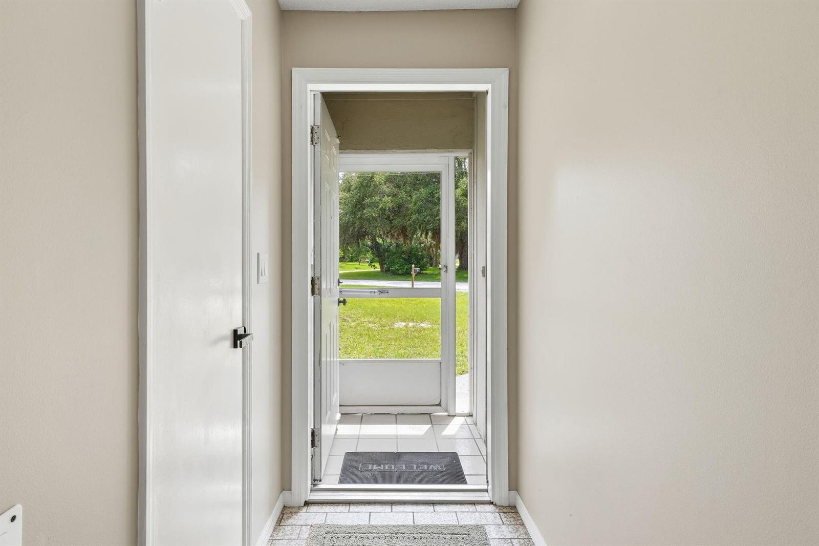 An interior entryway features a tiled floor, a white door, and a screen door opening outdoors — 273 Easy Street, Sebastian FL 32958, SEBASTIAN, FL