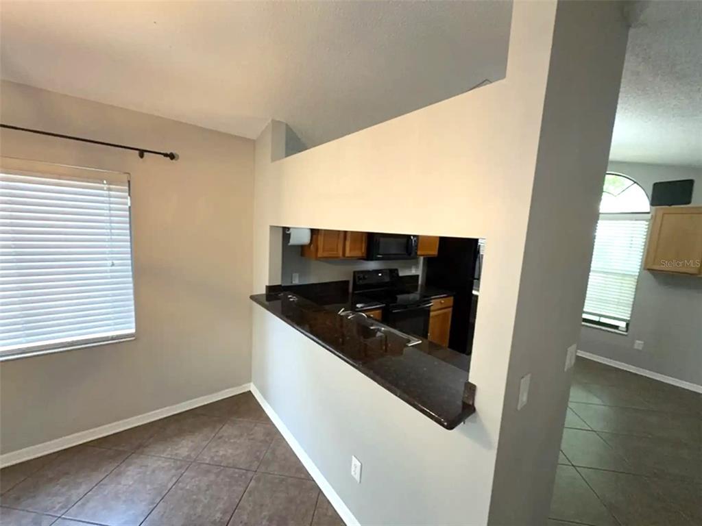 A kitchen with dark countertops and cabinets is visible through a pass-through window — 2201 GRASMERE DRIVE, APOPKA, FL