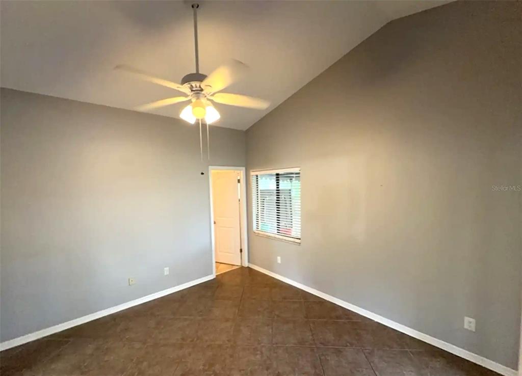 An empty room features gray walls, tile flooring, a ceiling fan, and a doorway — 2201 GRASMERE DRIVE, APOPKA, FL
