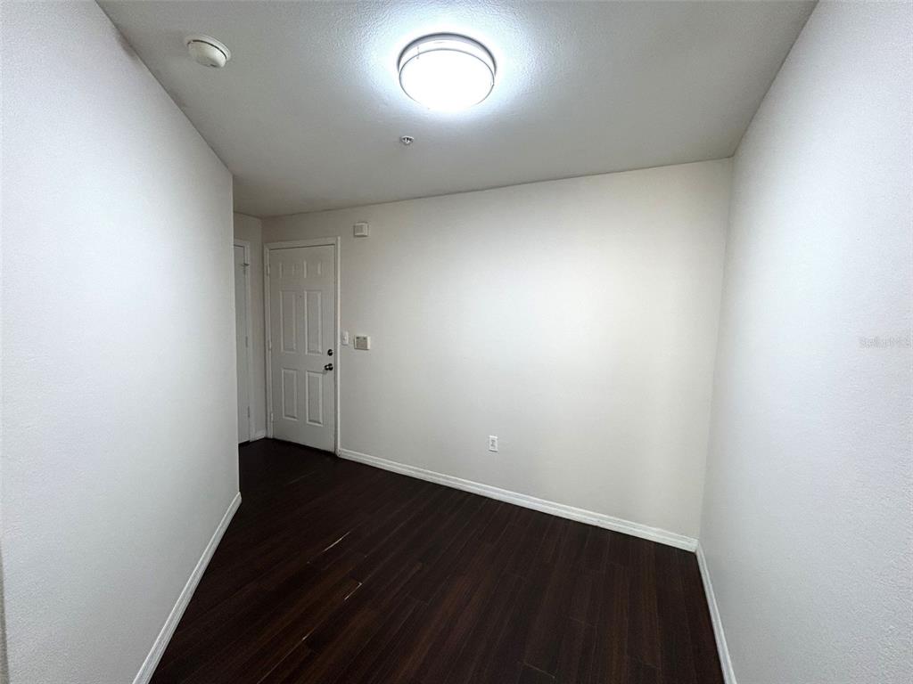 An empty room with white walls, dark wood-look flooring, and a central ceiling light fixture — 2015 ERVING CIRCLE UNIT 208, OCOEE, FL