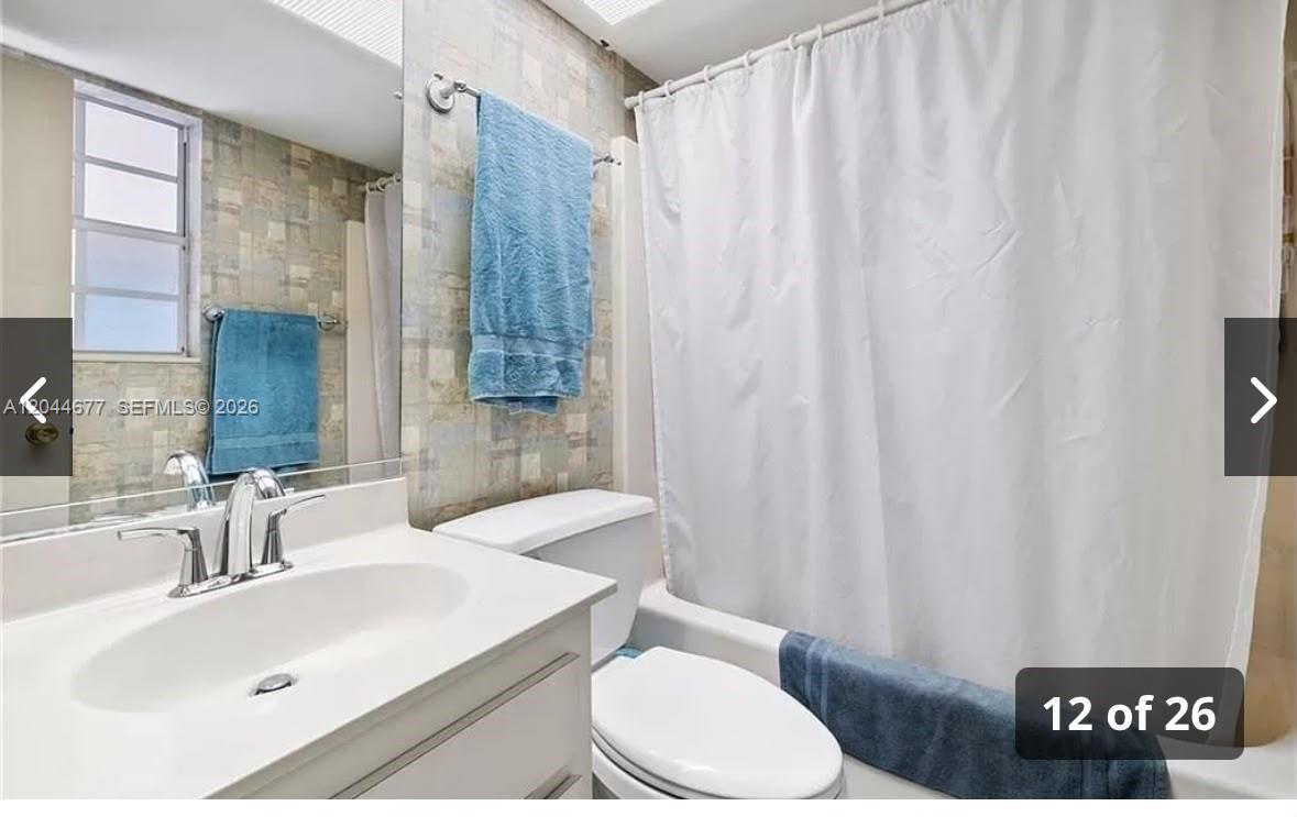 A bathroom features a white vanity, a toilet, and a shower with a white curtain — 4210 CINDY, Naples FL 34112, NAPLES, FL