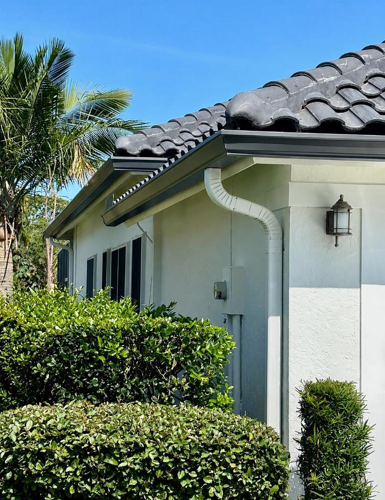 A white house exterior features a dark tiled roof, black gutters, and a white downspout — 4848 SE Mariner Village Lane, Stuart FL 34997, STUART, FL
