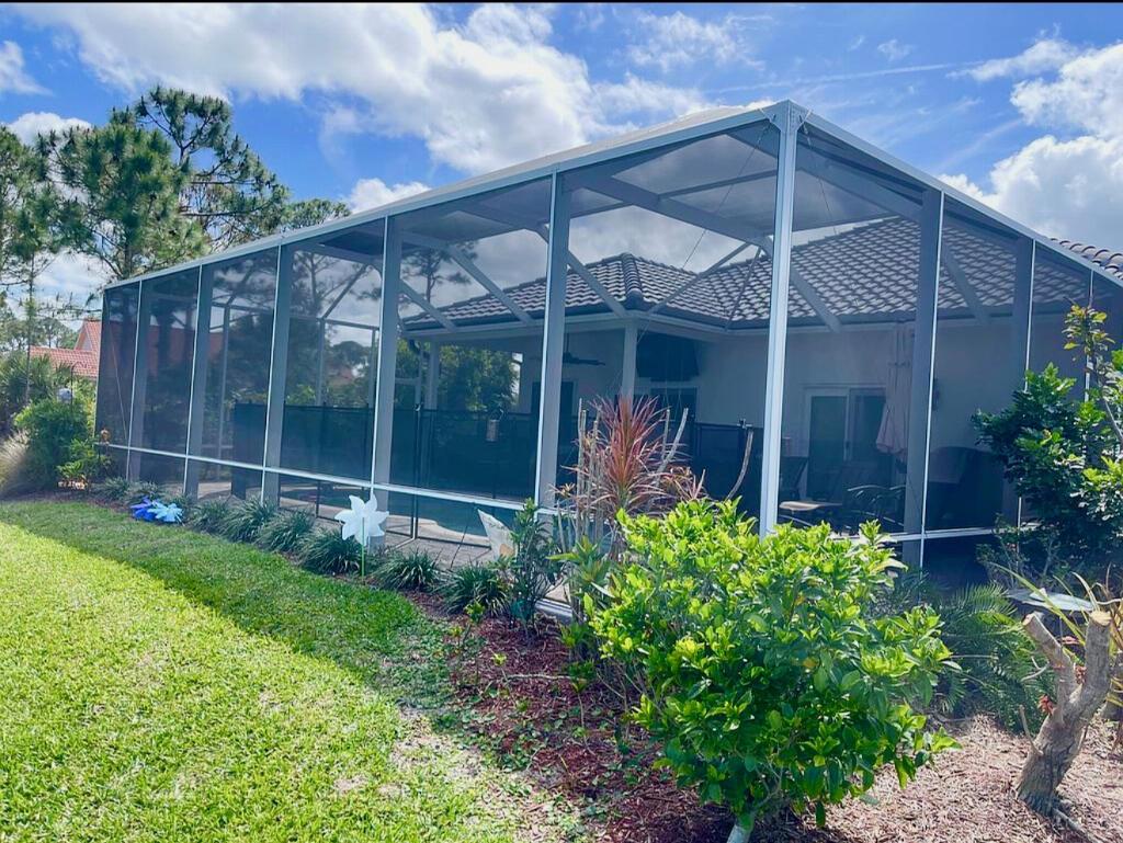 A screened-in patio enclosure with a pool sits behind a house with a tiled roof — 4848 SE Mariner Village Lane, Stuart FL 34997, STUART, FL