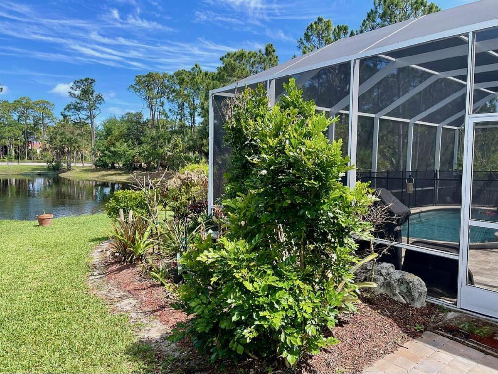 A green shrub sits beside a screened-in pool enclosure overlooking a small pond — 4848 SE Mariner Village Lane, Stuart FL 34997, STUART, FL