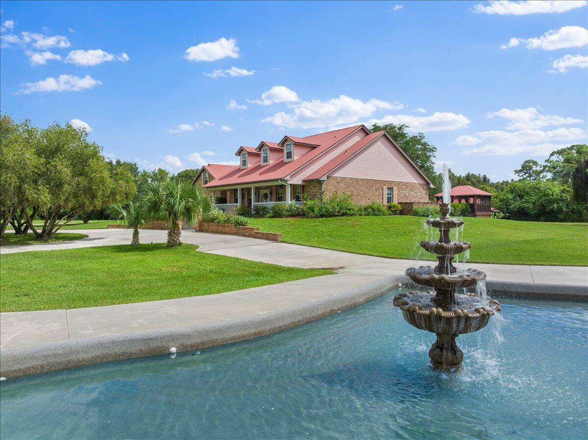 A multi-tiered fountain sits in the foreground of a house with a red metal roof — 930 90th Avenue, Vero Beach FL 32966, VERO BEACH, FL