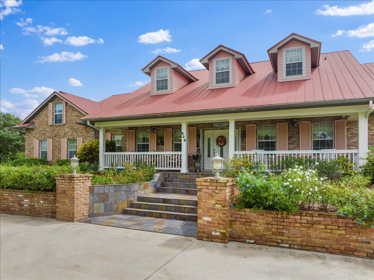 A brick house with a red metal roof and three dormer windows features a porch — 930 90th Avenue, Vero Beach FL 32966, VERO BEACH, FL