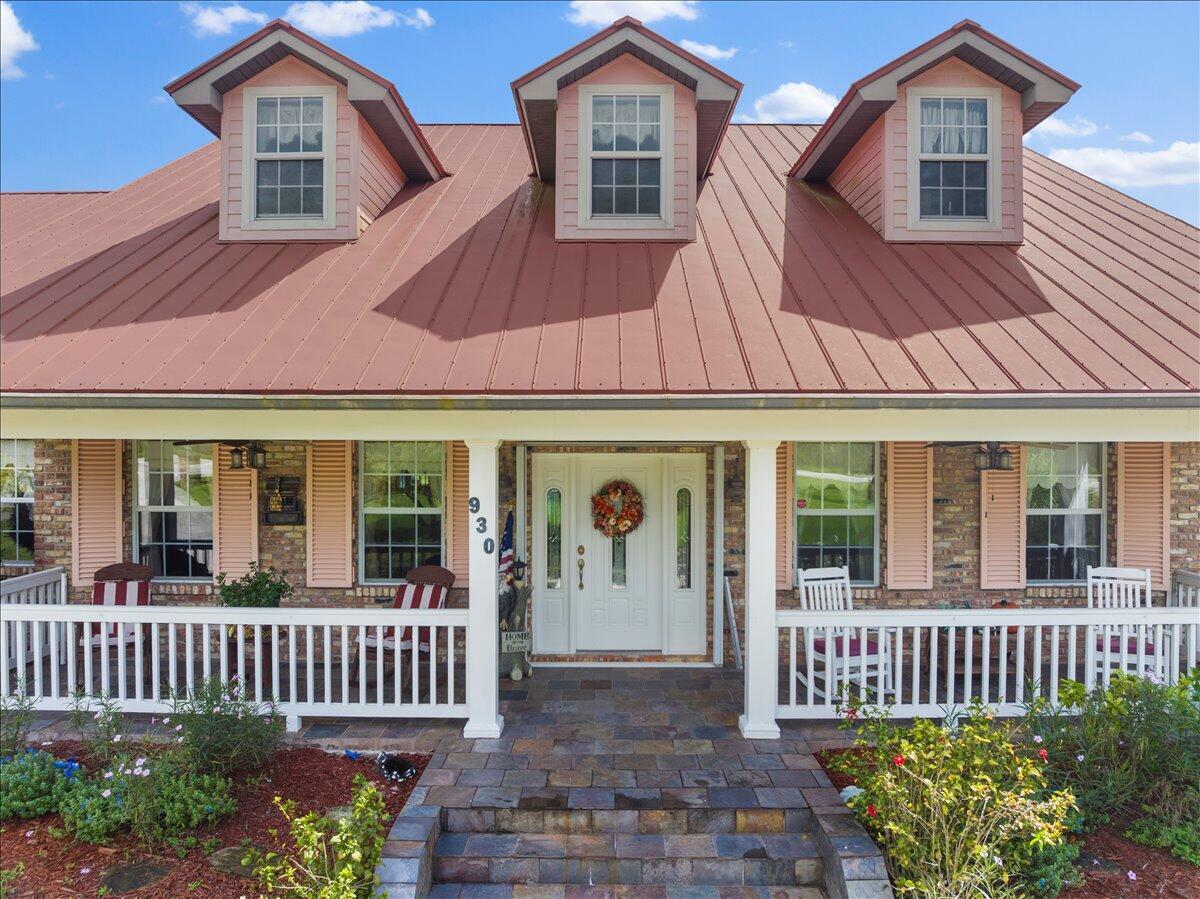 A single-story brick house features a red metal roof, three dormers, and a front porch — 930 90th Avenue, Vero Beach FL 32966, VERO BEACH, FL