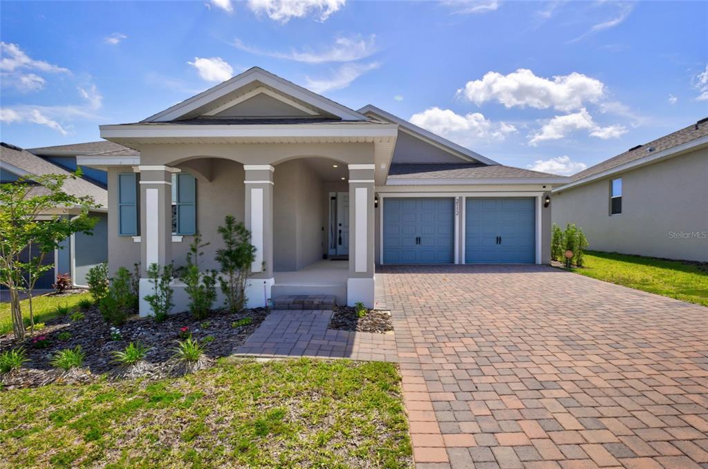 A single-story house features a paved driveway, a two-car garage, and a covered front porch — 2112 KEYSTONE PASS, MINNEOLA, FL