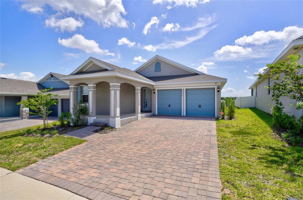 A single-story house with a paved driveway, two-car garage, and a covered front porch — 2112 KEYSTONE PASS, MINNEOLA, FL