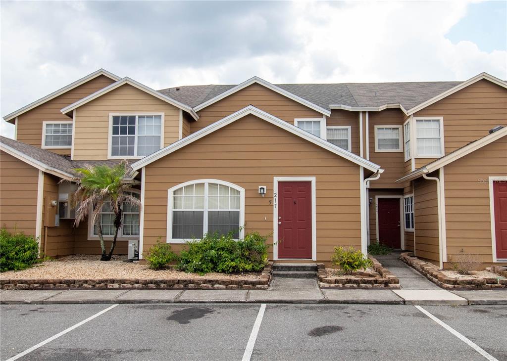 A two-story tan townhouse exterior with a red front door and a small palm tree — 217 AUSTRALIAN WAY UNIT A, DAVENPORT, FL