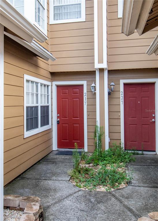 The exterior view shows two red front doors with house numbers on a concrete walkway — 217 AUSTRALIAN WAY UNIT A, DAVENPORT, FL