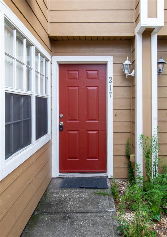 A red front door with a lockbox is set in a tan exterior wall — 217 AUSTRALIAN WAY UNIT A, DAVENPORT, FL