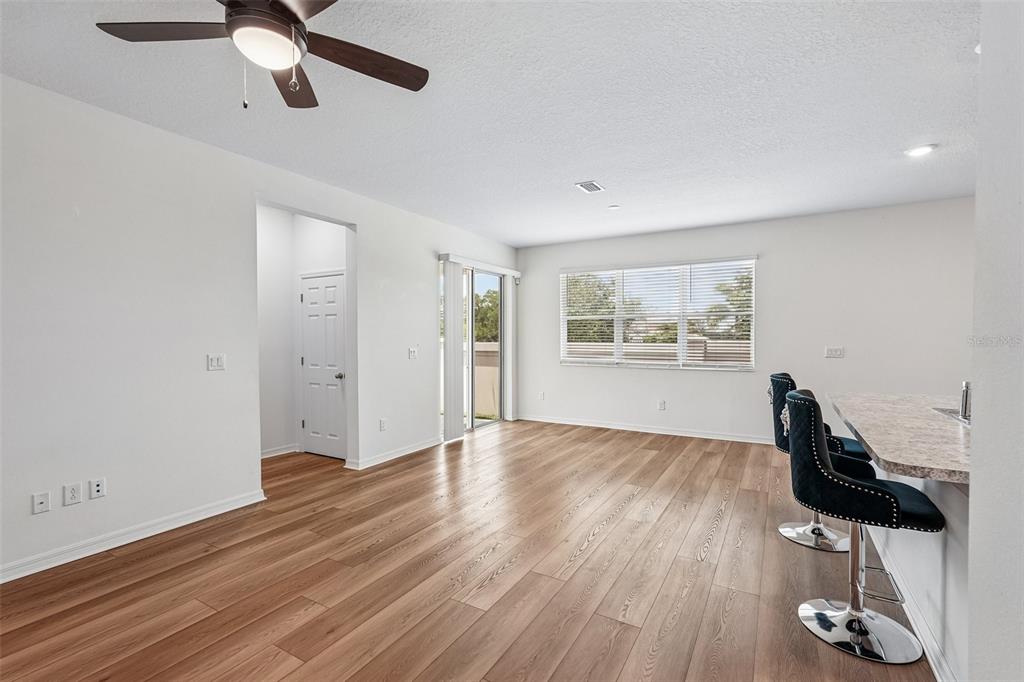 An open-concept kitchen and living area featuring dark wood cabinets, stainless appliances, and wood flooring — 2896 89TH STREET CIRCLE E, PALMETTO, FL