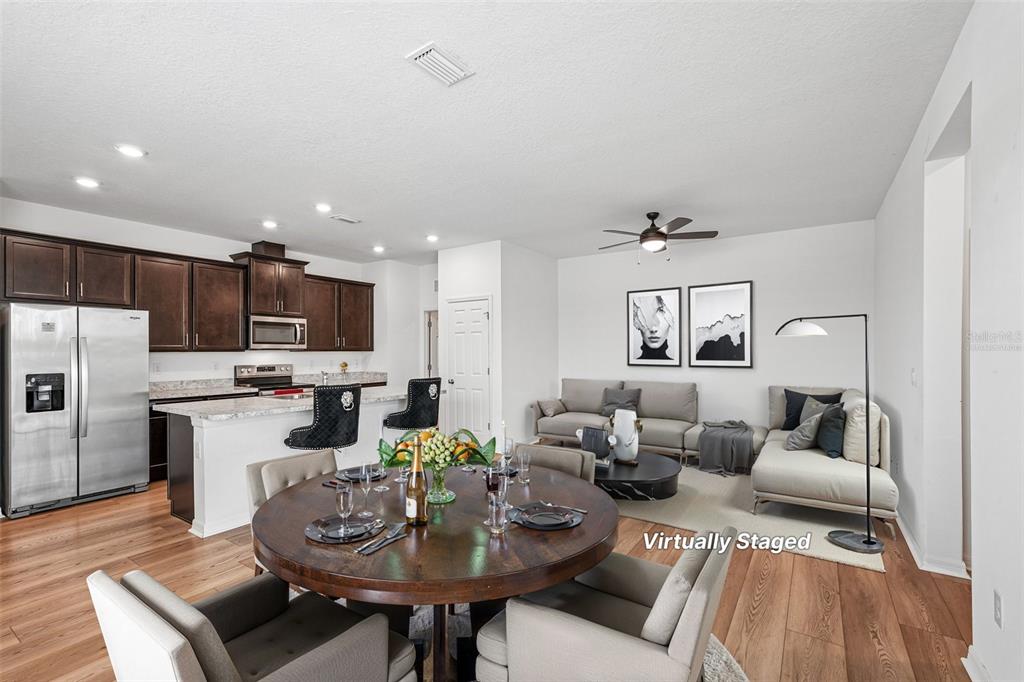 A kitchen with dark wood cabinets and a breakfast bar opens into a living area — 2896 89TH STREET CIRCLE E, PALMETTO, FL