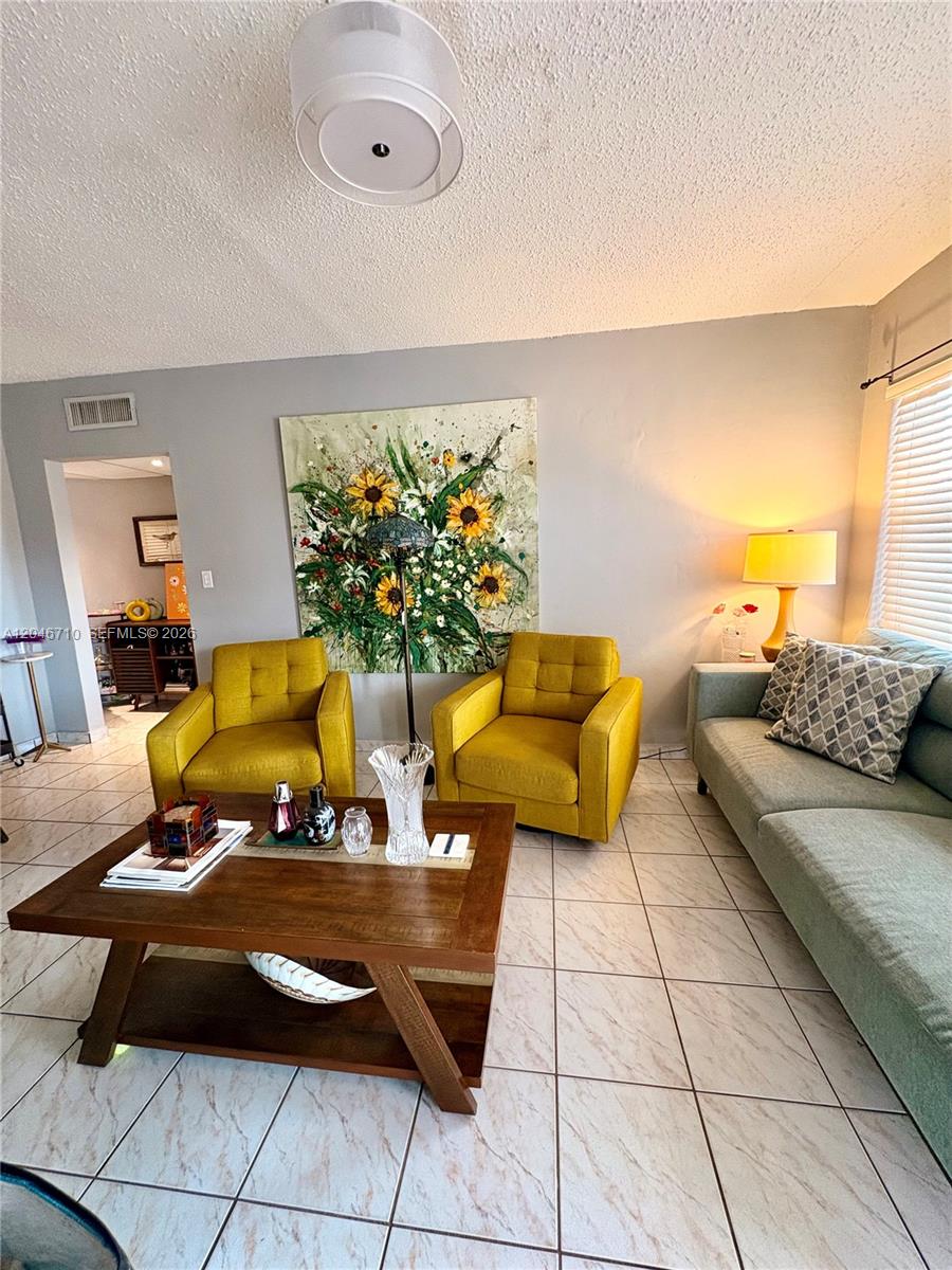 A living room features two yellow armchairs, a wooden coffee table, and a large sunflower painting — 3501 SW 10th St # 1B, Miami FL 33135, MIAMI, FL