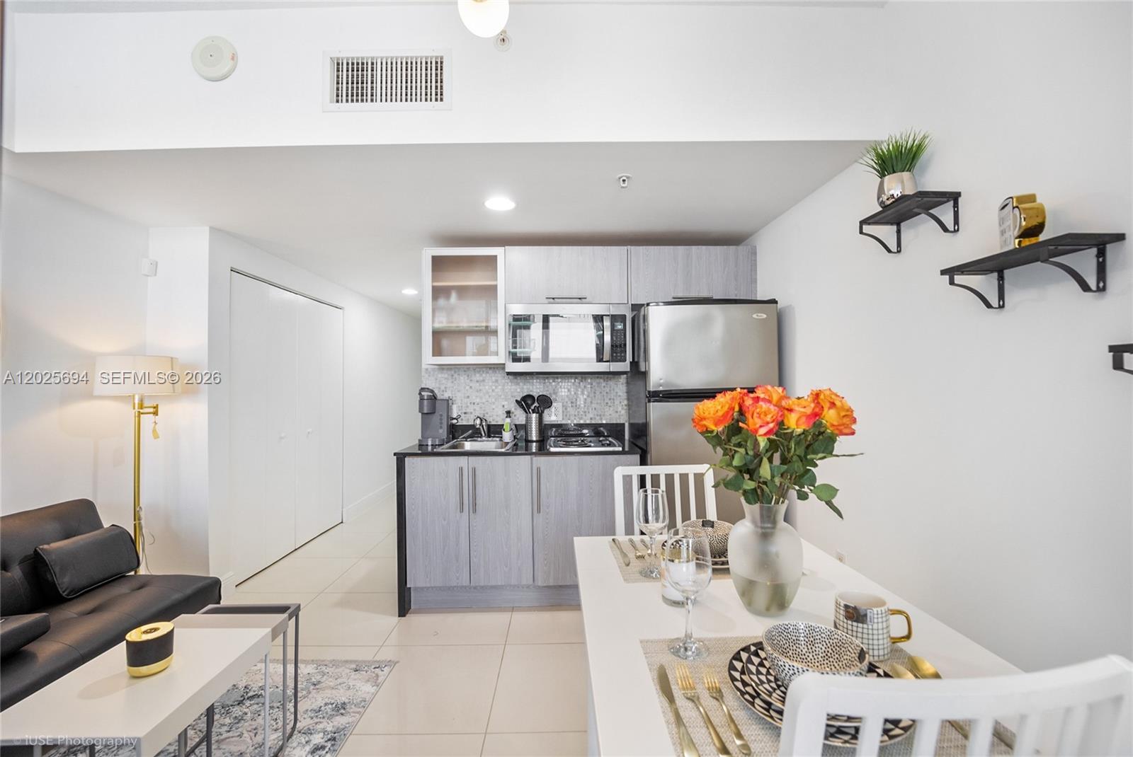 A small kitchen with gray cabinets and stainless steel appliances sits beside a dining area — 1750 N Bayshore Dr # 1219, Miami FL 33132, MIAMI, FL