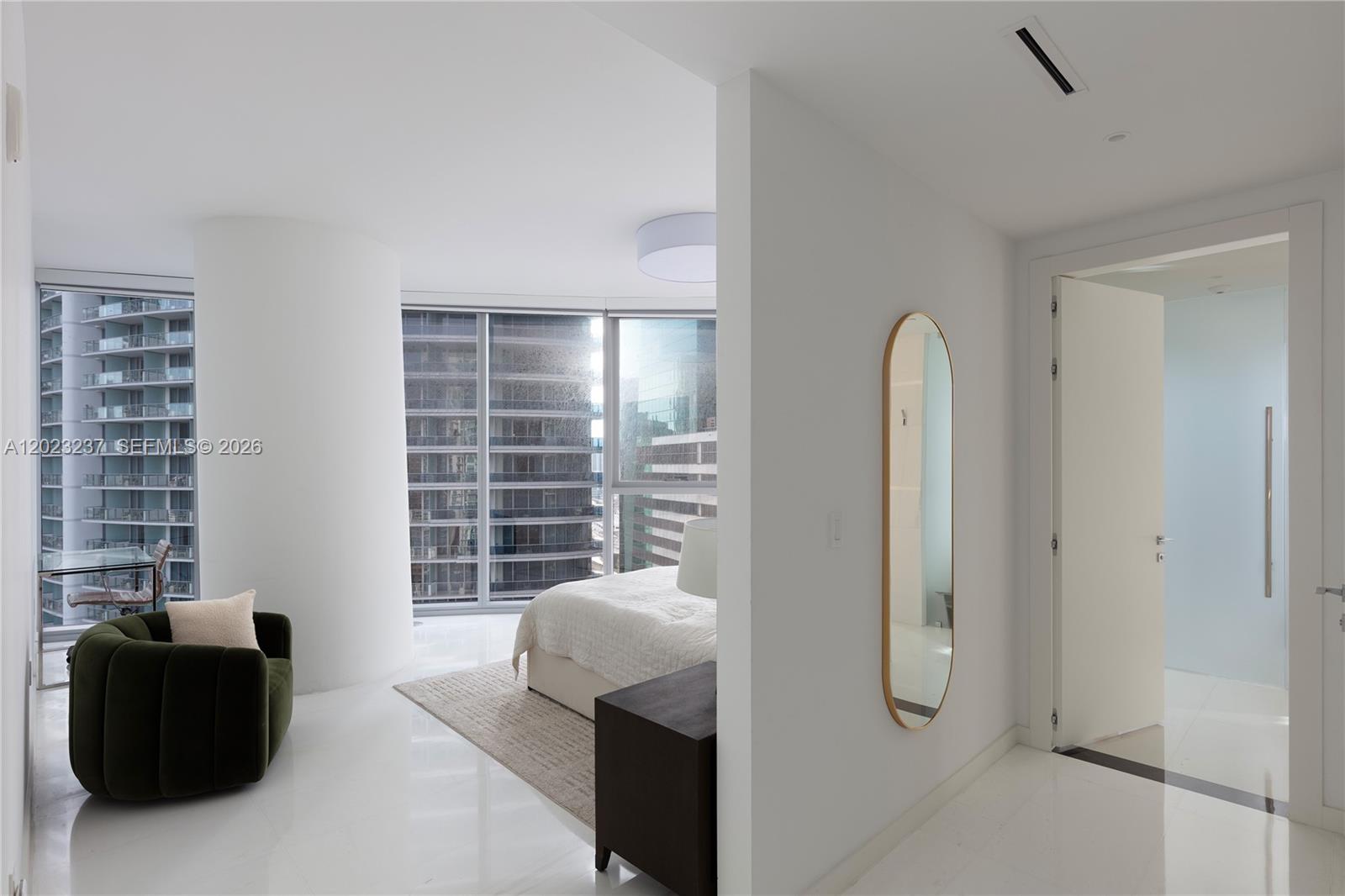 A modern bedroom features white tile floors, a green armchair, and floor-to-ceiling windows — 300 S Biscayne Blvd Way # 2107, Miami FL 33131, MIAMI, FL