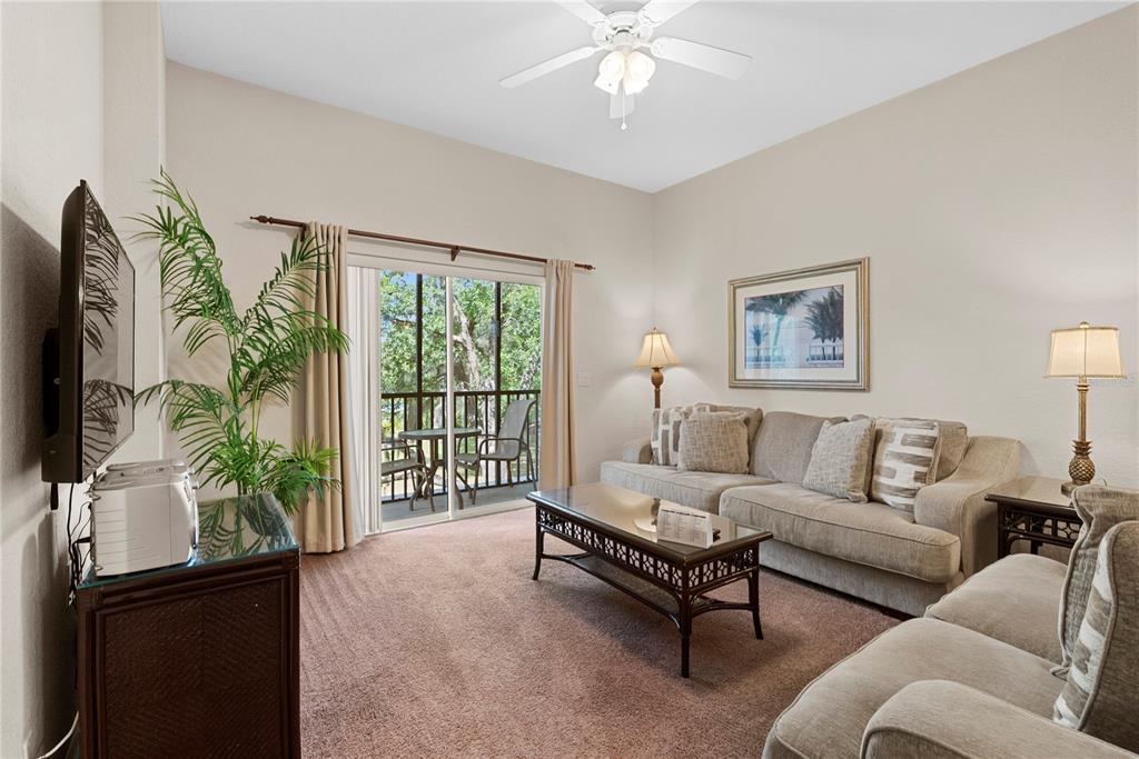 A living room features a beige sofa, a coffee table, and a sliding glass door — 806 GRAN BAHAMA BOULEVARD UNIT 30806, DAVENPORT, FL