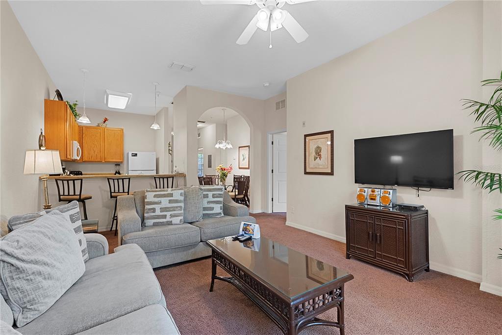 A living room with carpeted floors, a television, and an open view of the kitchen — 806 GRAN BAHAMA BOULEVARD UNIT 30806, DAVENPORT, FL