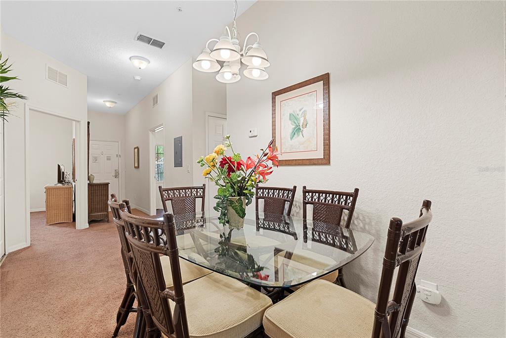 A dining room features a glass-topped table with six wooden chairs under a chandelier — 806 GRAN BAHAMA BOULEVARD UNIT 30806, DAVENPORT, FL