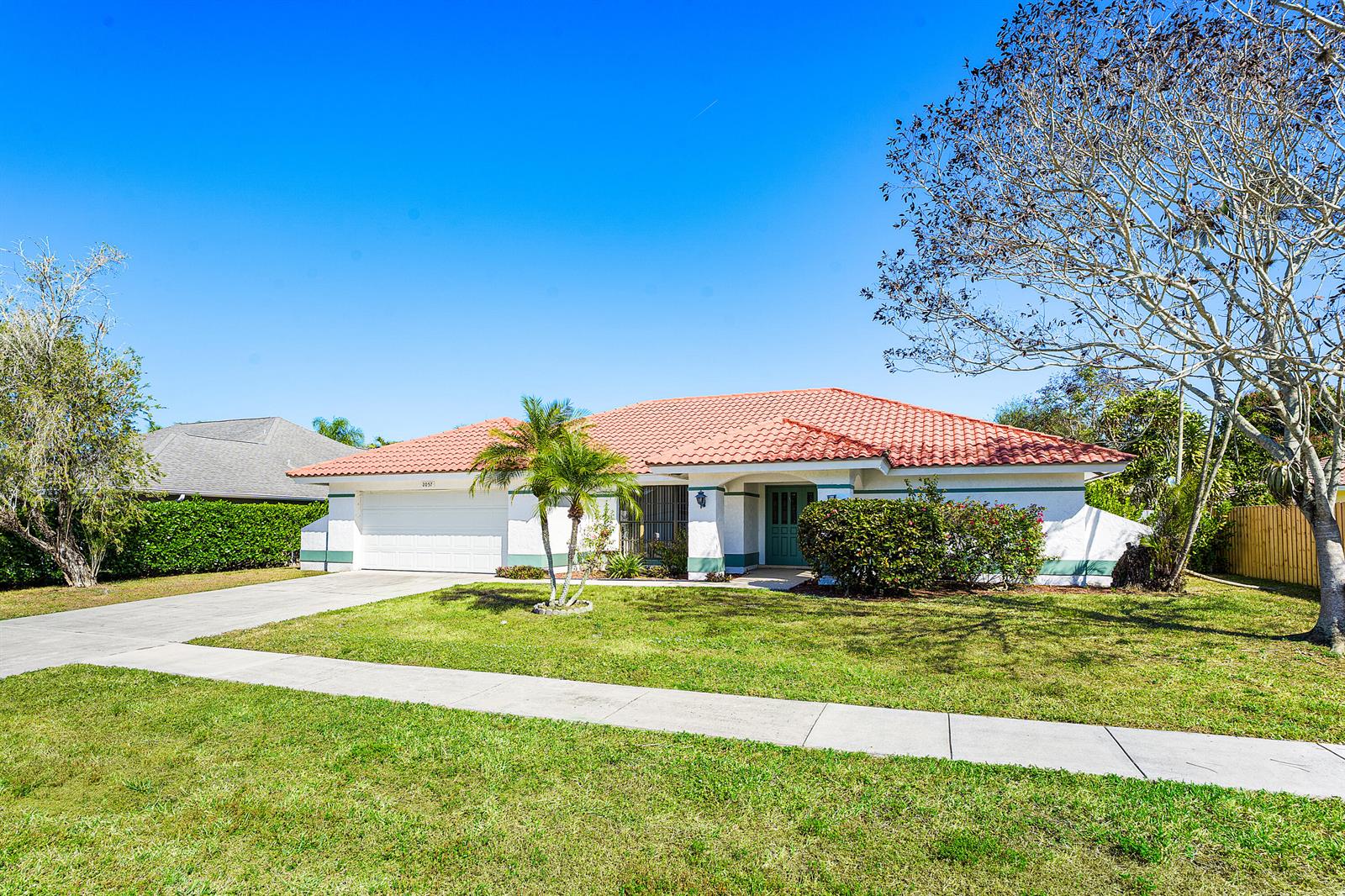 A single-story house with a red tile roof, white stucco walls, and a green door — 2057 Amesbury Circle, Wellington FL 33414, WELLINGTON, FL