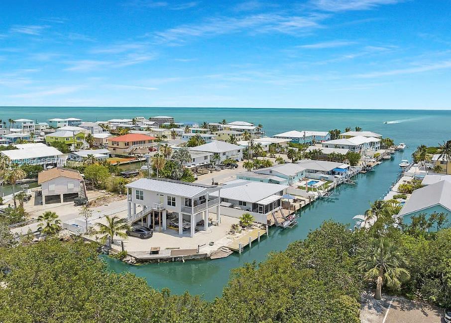An aerial view shows elevated houses along a canal leading to the open ocean — 425 89th Street Ocean, Marathon FL 33050, MARATHON, FL