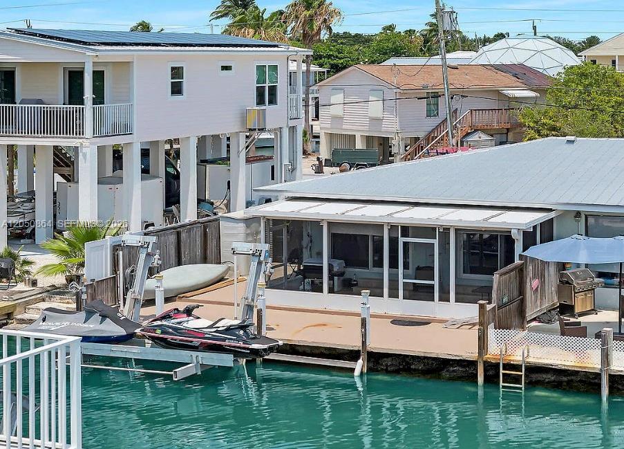 An elevated house and a waterfront home with a boat lift and jet skis — 425 89th Street Ocean, Marathon FL 33050, MARATHON, FL