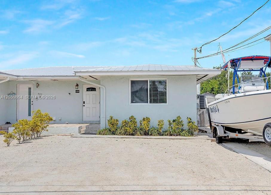 A light-colored single-story house with a white door and a boat parked on a trailer — 425 89th Street Ocean, Marathon FL 33050, MARATHON, FL